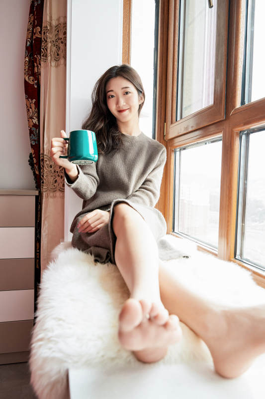 躺在舒适的飘窗上喝咖啡的少女