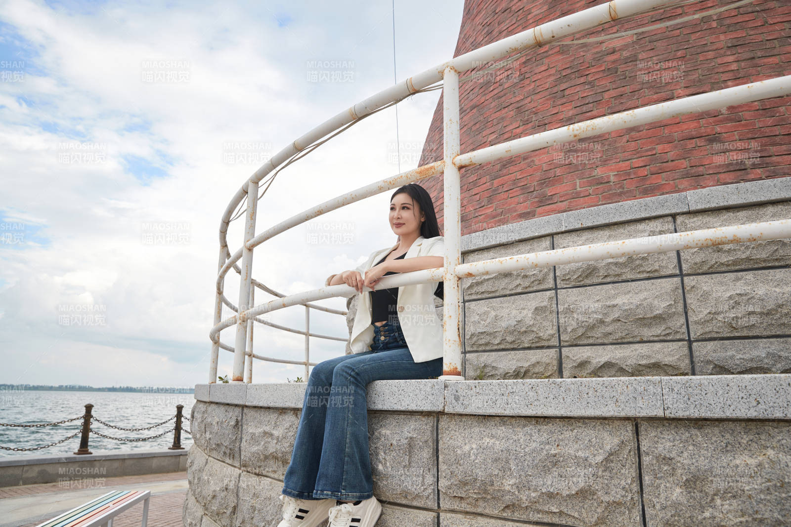 盛夏在景区湖边灯塔上拍照游玩的美女