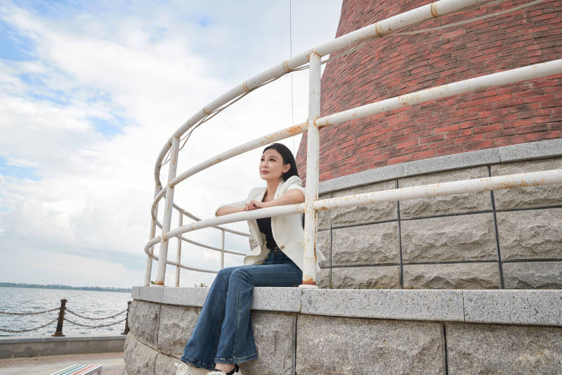 盛夏在景区湖边灯塔上拍照游玩的美女