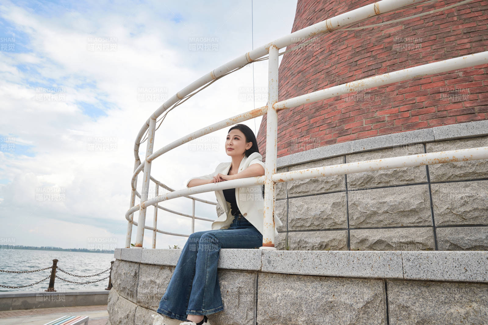 盛夏在景区湖边灯塔上拍照游玩的美女