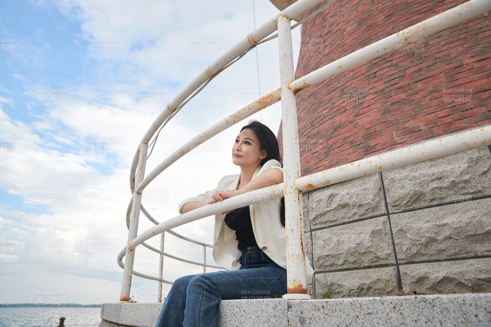 盛夏在景区湖边灯塔上拍照游玩的美女