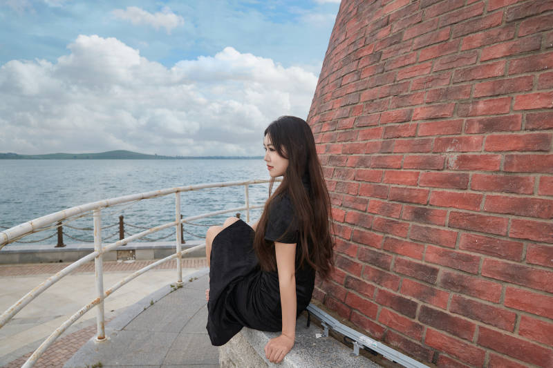 盛夏在景区湖边灯塔上拍照游玩的美女