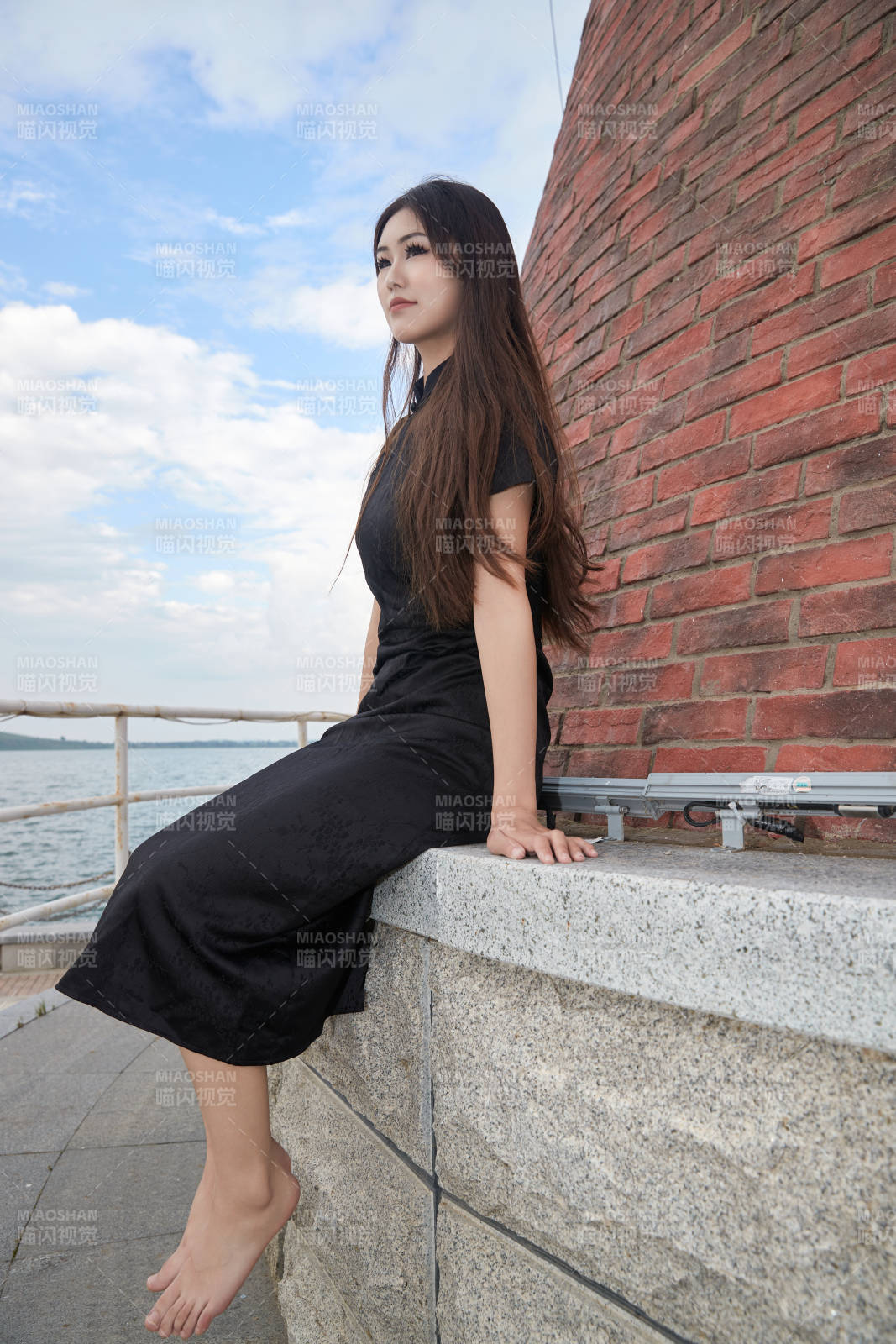 盛夏在景区湖边灯塔上拍照游玩的美女