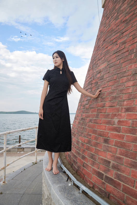 盛夏在景区湖边灯塔上拍照游玩的美女