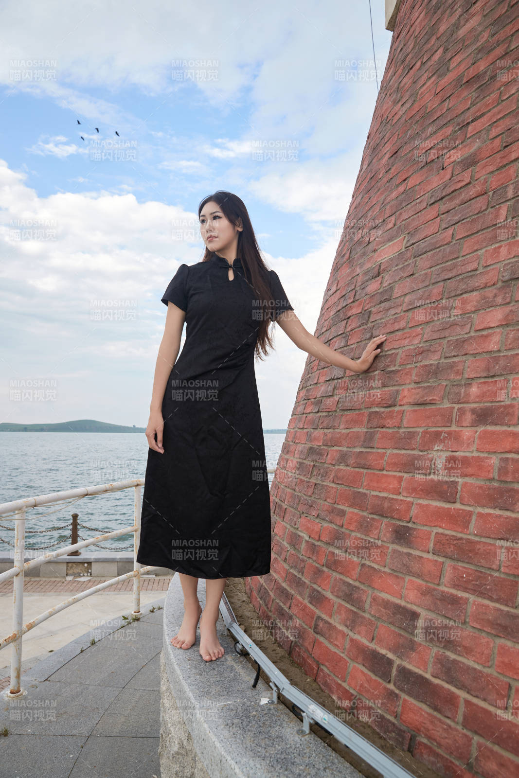 盛夏在景区湖边灯塔上拍照游玩的美女