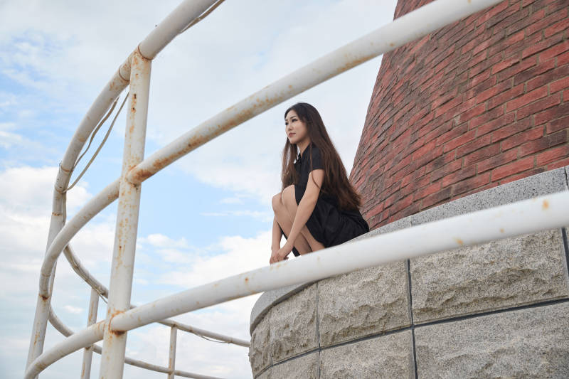 盛夏在景区湖边灯塔上拍照游玩的美女