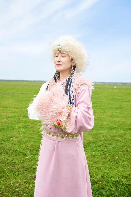 身穿藏族服饰在草原景区拍照的美女