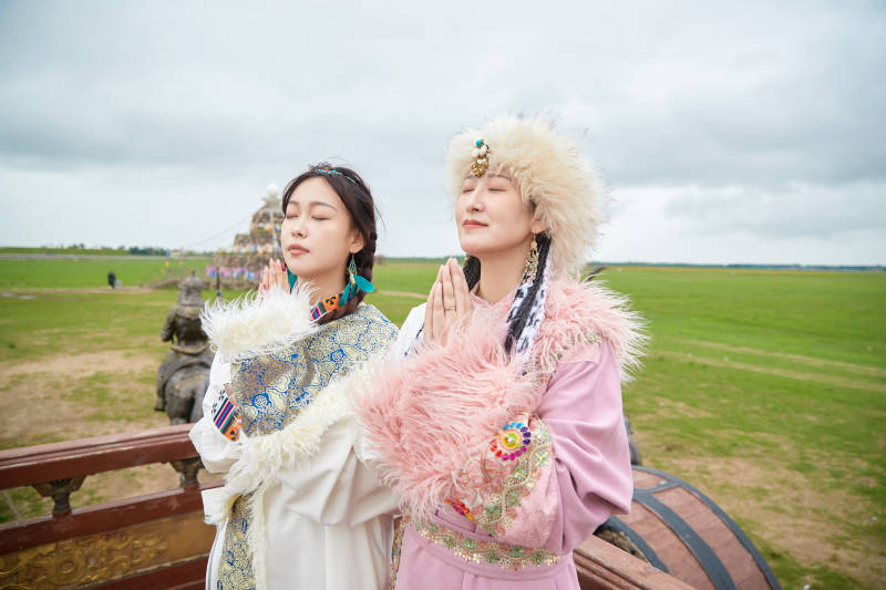 身穿藏族服饰在草原拍照游玩的闺蜜