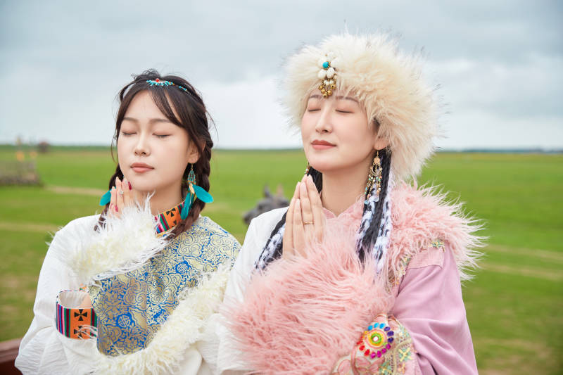 身穿藏族服饰在草原拍照游玩的闺蜜