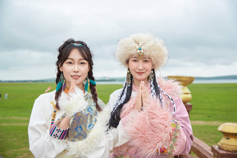 身穿藏族服饰在草原拍照游玩的闺蜜