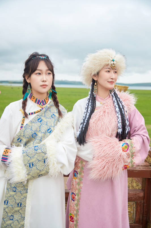 身穿藏族服饰在草原拍照游玩的闺蜜