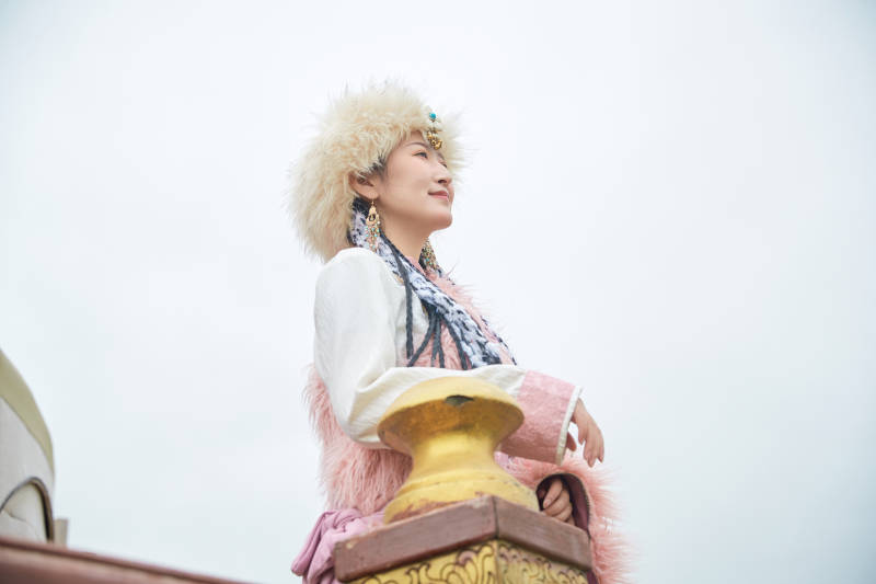 身穿藏族服饰在草原景区拍照的美女