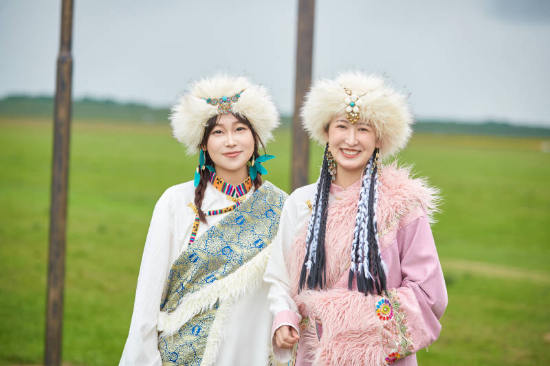 身穿藏族服饰在草原拍照游玩的闺蜜