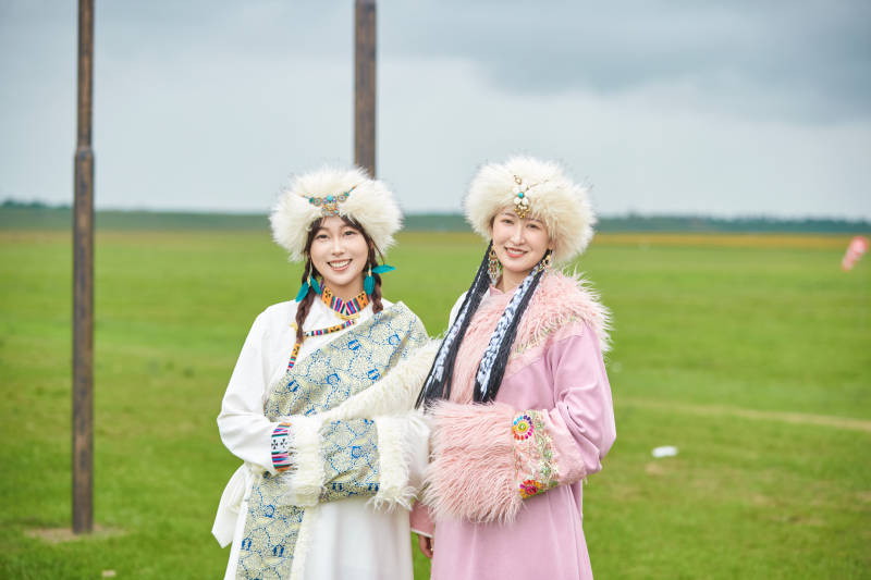 身穿藏族服饰在草原拍照游玩的闺蜜