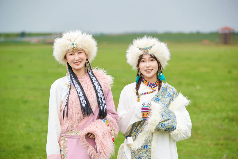 身穿藏族服饰在草原拍照游玩的闺蜜