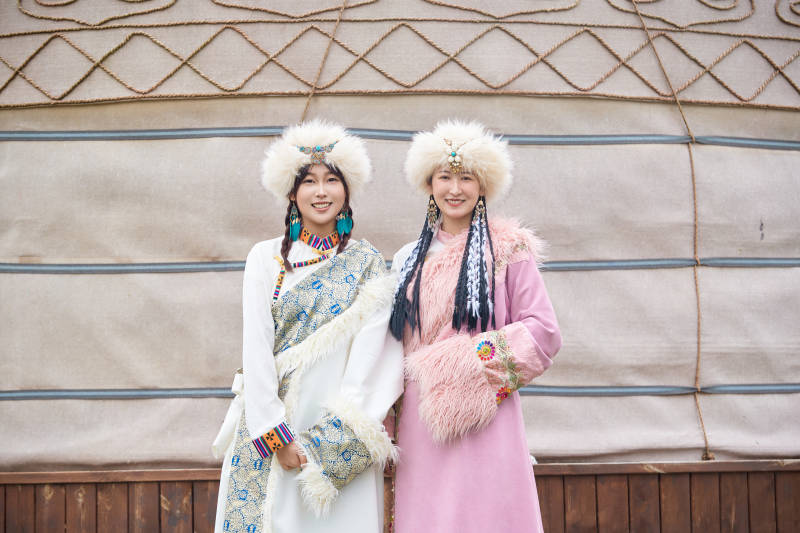 身穿藏族服饰在草原拍照游玩的闺蜜