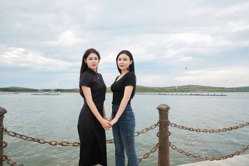 在旅游区湖边打卡点拍照的美女闺蜜