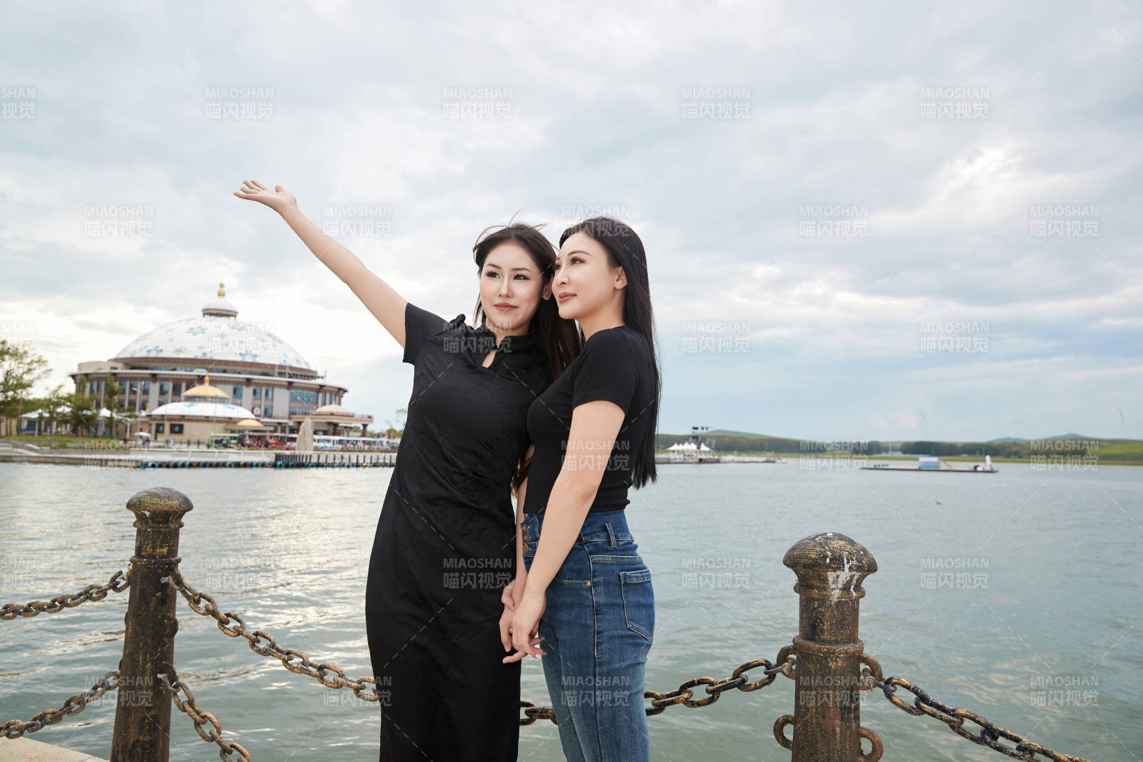 在旅游区湖边打卡点拍照的美女闺蜜