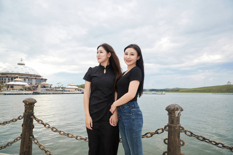 在旅游区湖边打卡点拍照的美女闺蜜