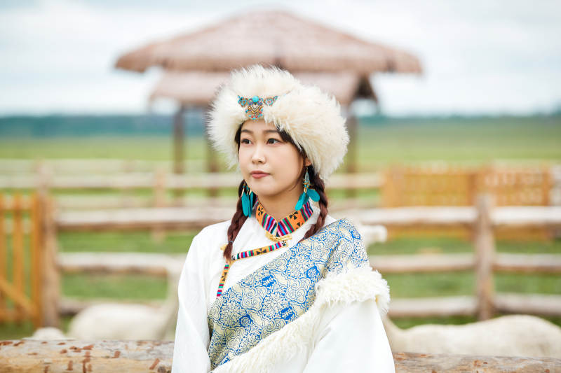 穿藏族服饰的姑娘在羊驼饲养基地拍照