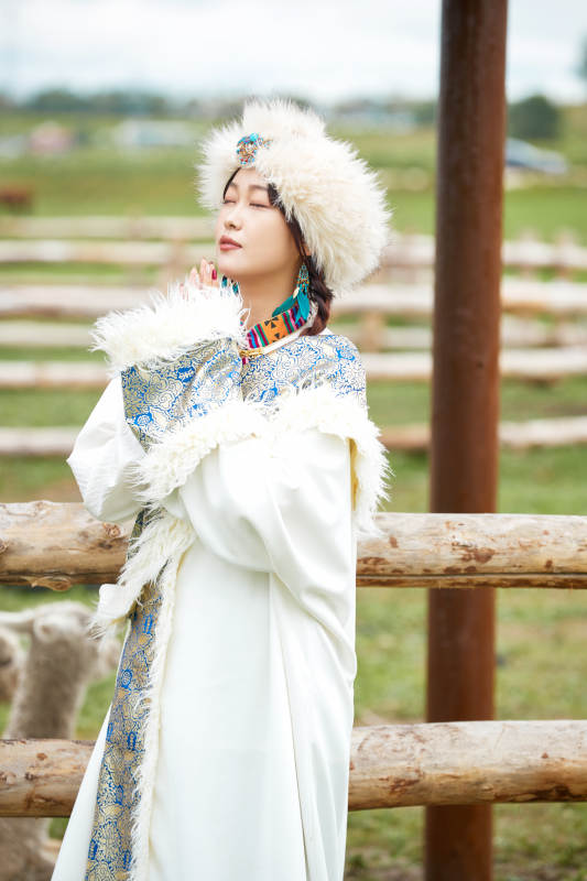 穿藏族服饰的姑娘在羊驼饲养基地拍照