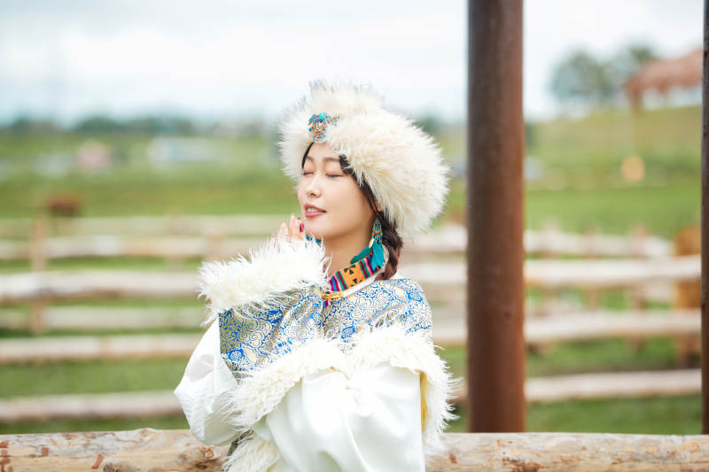 穿藏族服饰的姑娘在羊驼饲养基地拍照