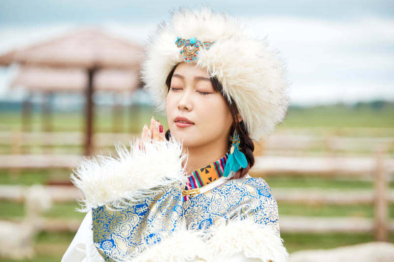 穿藏族服饰的姑娘在羊驼饲养基地拍照