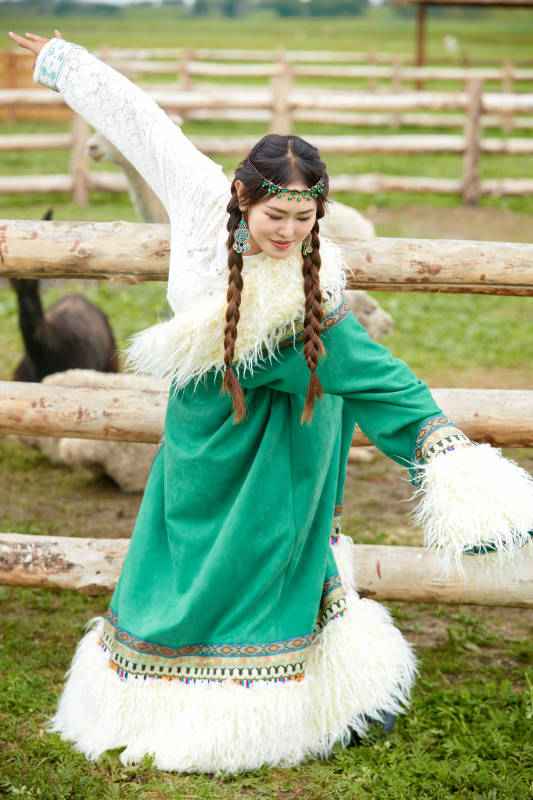 穿藏族服饰的姑娘在羊驼饲养基地拍照