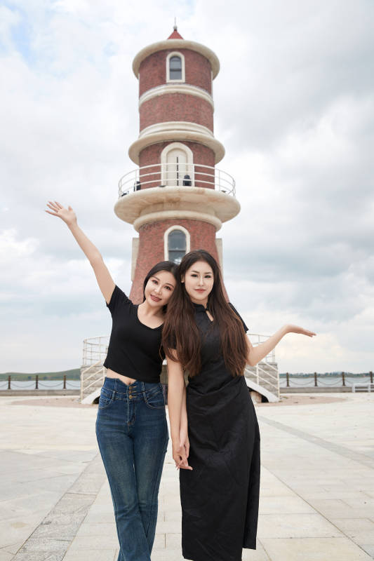 在旅游区湖边打卡点拍照的美女闺蜜