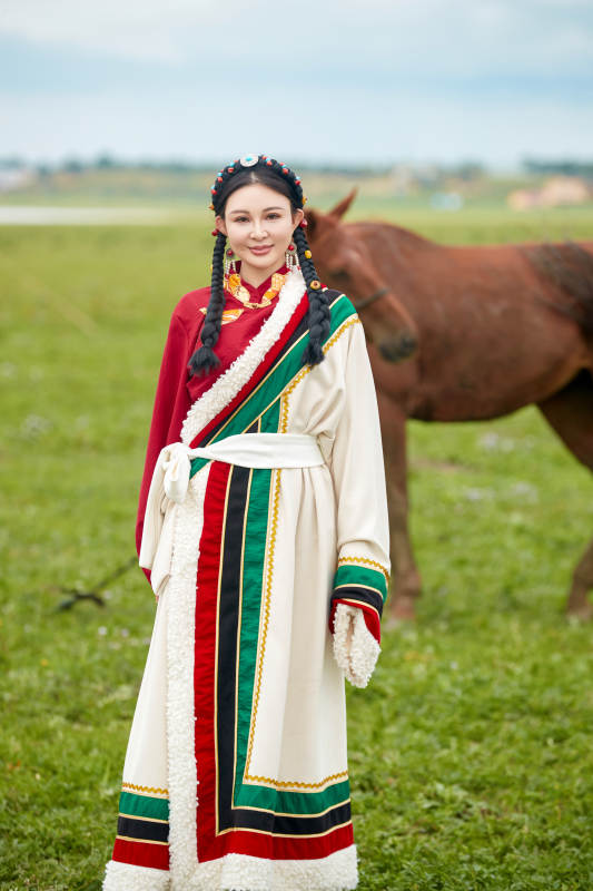 身穿藏族服饰和马匹拍照的美女