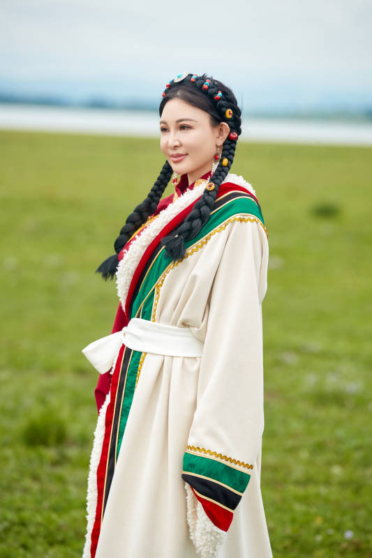 身穿红色藏族服饰在草原景区拍照的美女