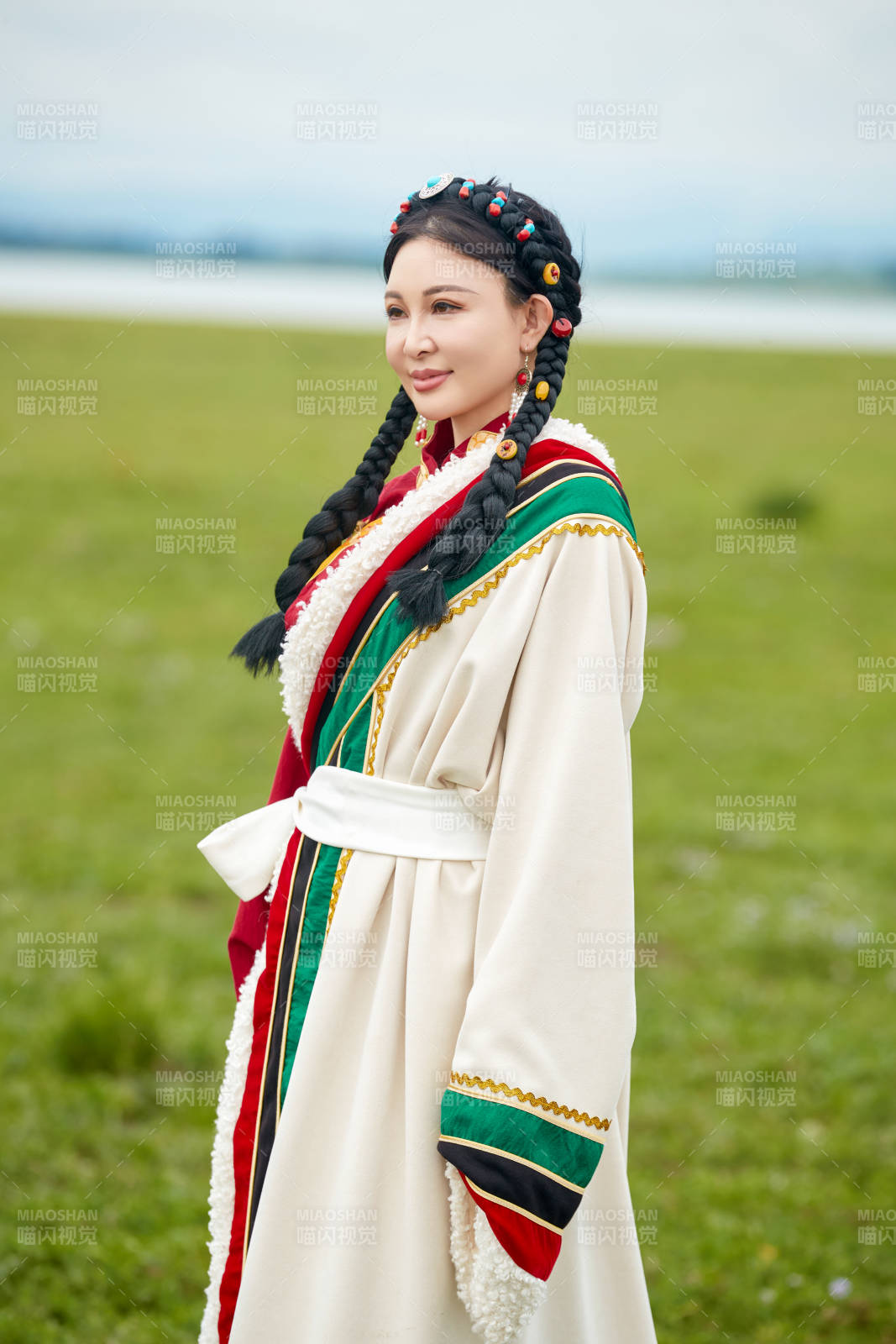 身穿红色藏族服饰在草原景区拍照的美女