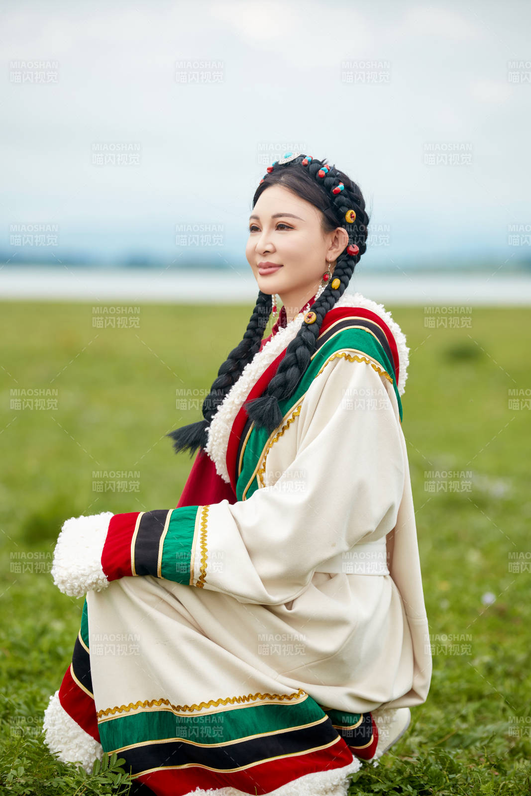 身穿红色藏族服饰在草原景区拍照的美女