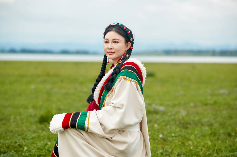 身穿红色藏族服饰在草原景区拍照的美女