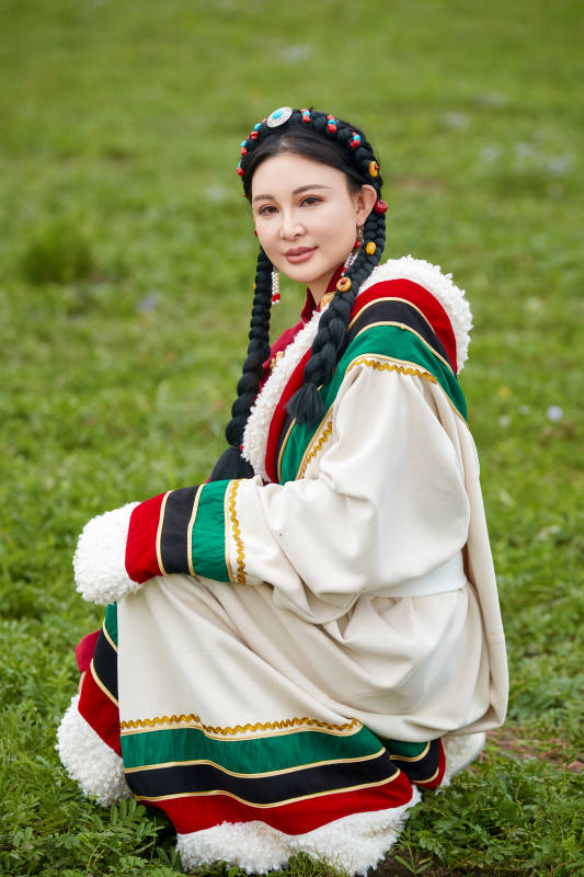 身穿红色藏族服饰在草原景区拍照的美女
