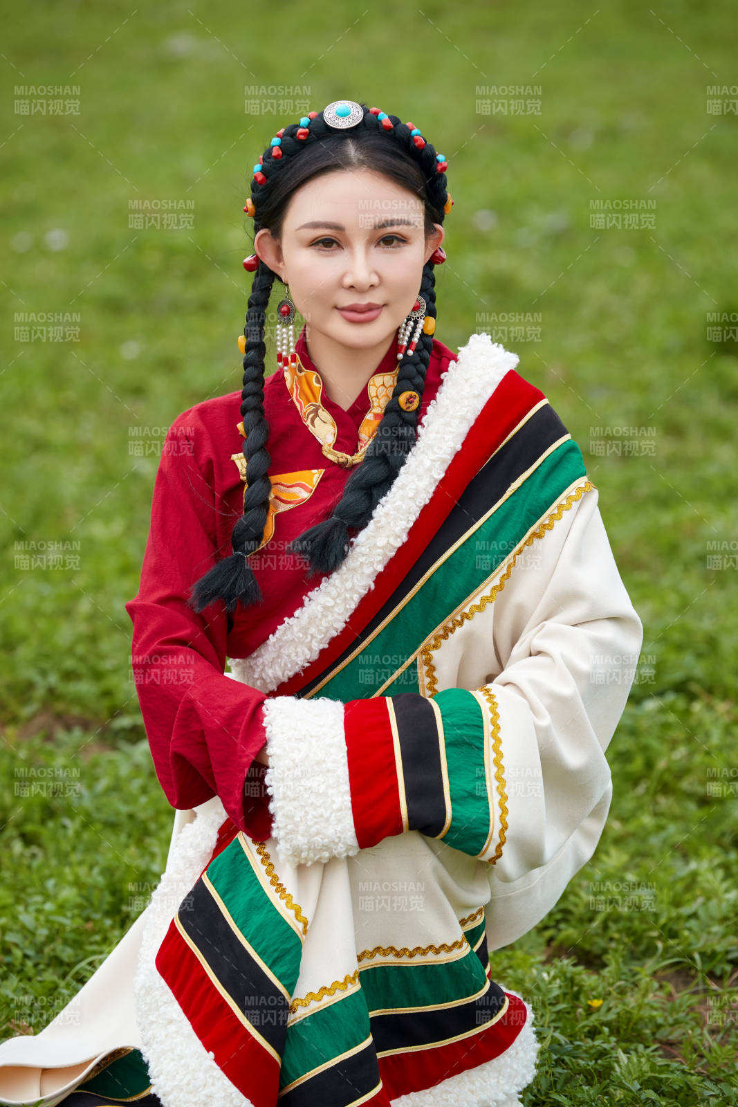 身穿红色藏族服饰在草原景区拍照的美女