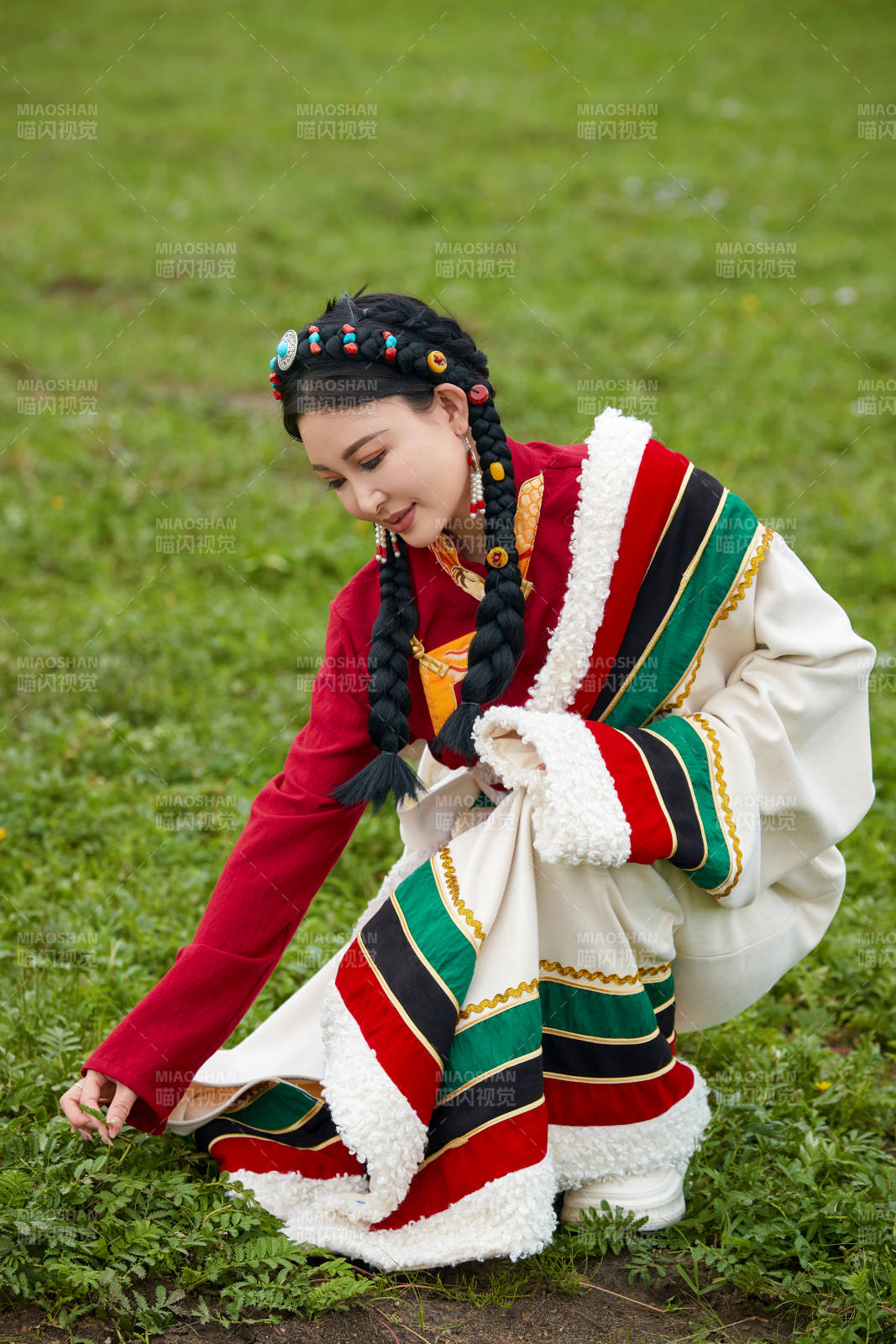 身穿红色藏族服饰在草原景区拍照的美女