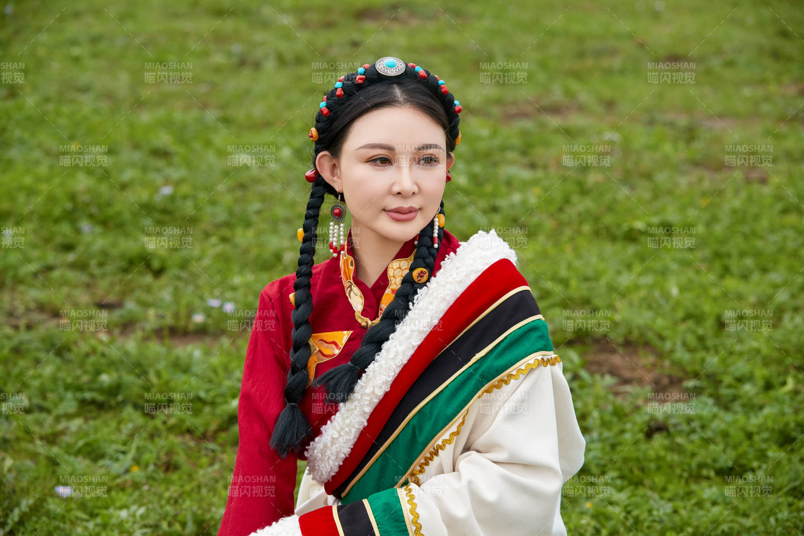 身穿红色藏族服饰在草原景区拍照的美女