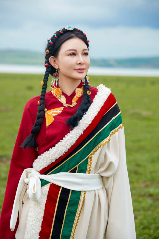 身穿红色藏族服饰在草原景区拍照的美女