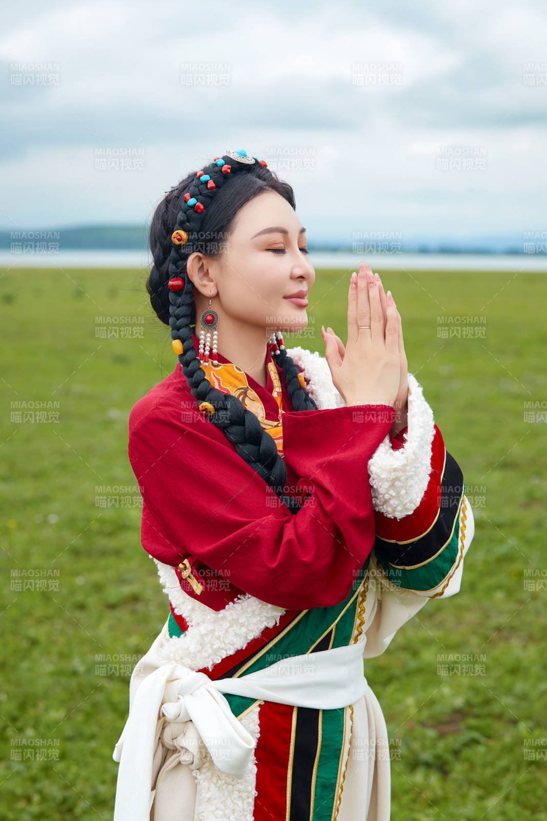 身穿紅色藏族服飾在草原景區拍照的美女