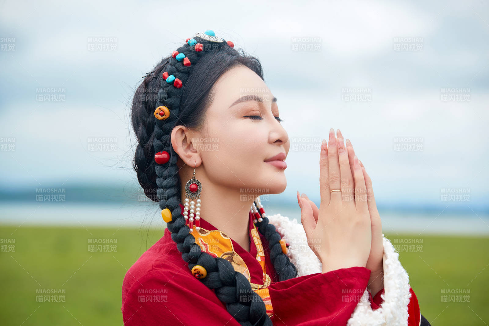 身穿紅色藏族服飾在草原景區拍照的美女