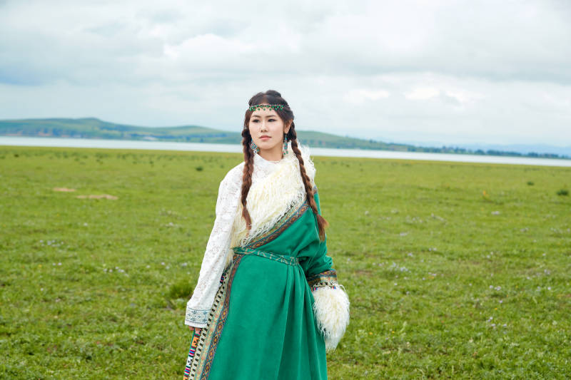 身穿绿色藏族服饰在草原跳舞的美女