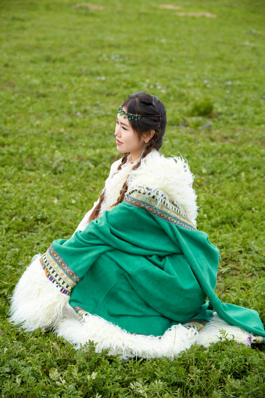 身穿绿色藏族服饰在草原跳舞的美女