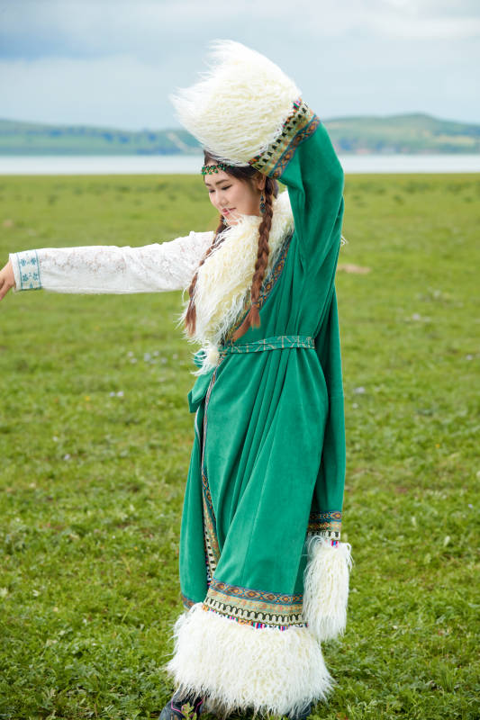 身穿绿色藏族服饰在草原跳舞的美女