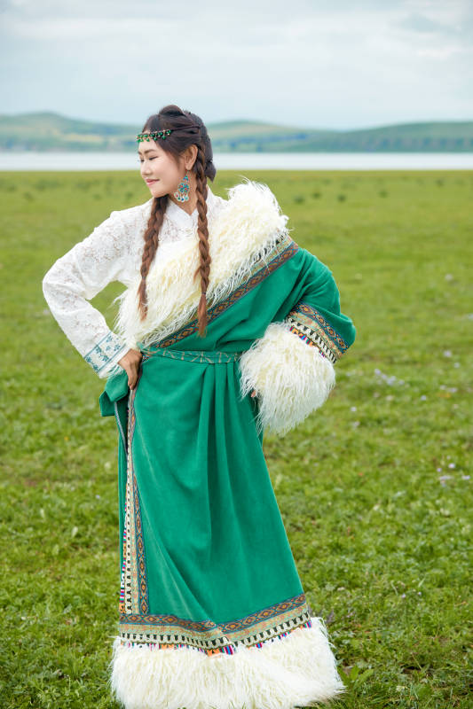 身穿绿色藏族服饰在草原跳舞的美女