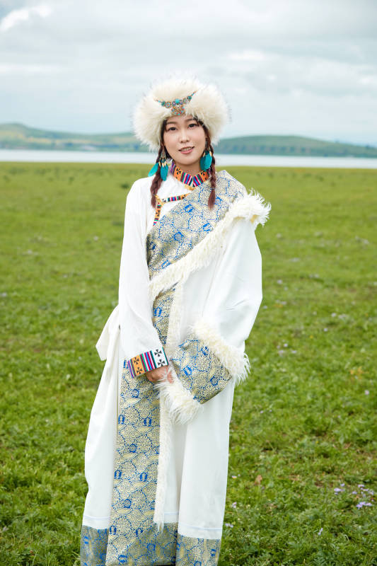 穿白色藏族服饰在草原拍照的少女