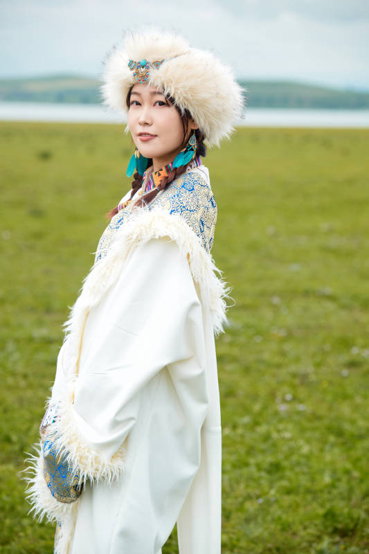穿白色藏族服饰在草原拍照的少女