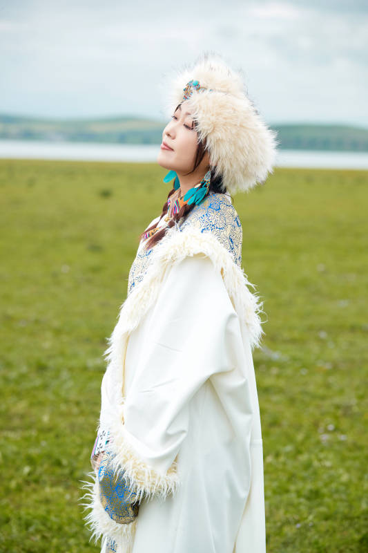 穿白色藏族服饰在草原拍照的少女