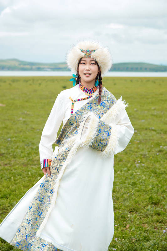 穿白色藏族服饰在草原拍照的少女