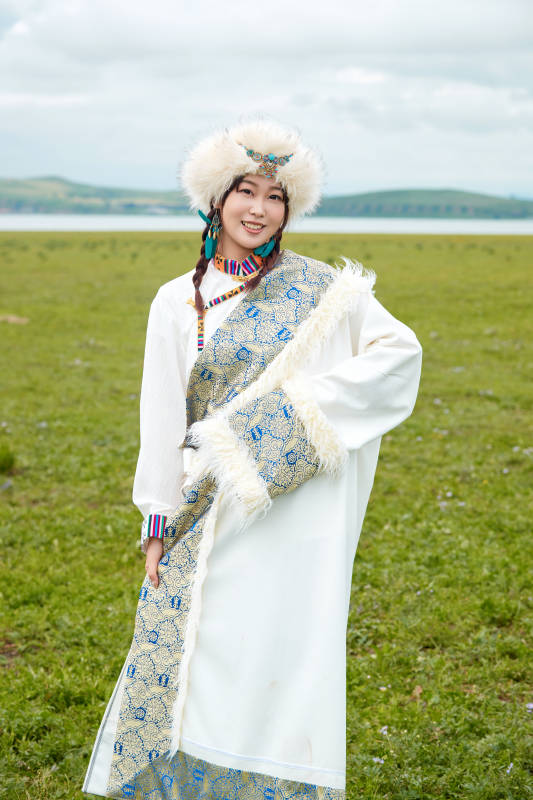 穿白色藏族服饰在草原拍照的少女